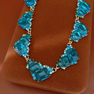 Primer plano de un collar vintage con piedras cuadradas azules sobre soporte de terciopelo café.