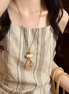 Detailed view of bohemian style woven long necklace worn with a striped linen dress