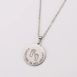 Detailed macro view of silver stainless steel pendant with baby feet and heart text