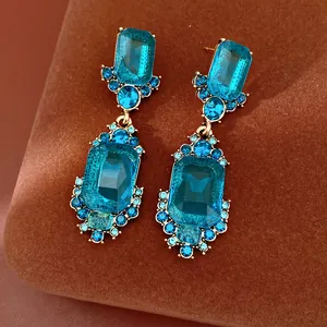 Vista detallada de pendientes vintage de cristal azul con montura dorada clásica