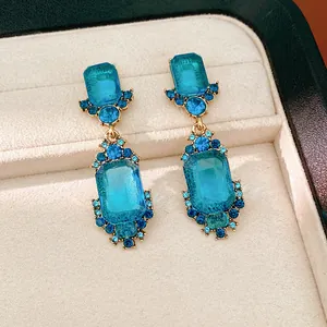 Vista detallada de pendientes vintage con cristales azules en una bandeja de joyas de terciopelo