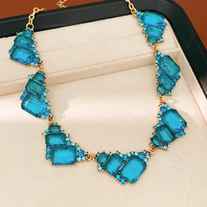 Vista detallada de un collar vintage dorado con gemas azules en un estuche de joyería