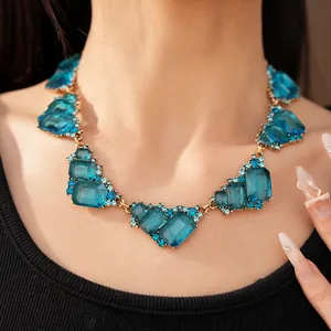 Detalle del collar vintage geométrico de cristal azul en modelo con arte de uñas
