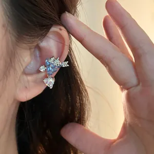 Primo piano di un ear cuff a uva in zircone con un cuore pendente indossato sull'orecchio.