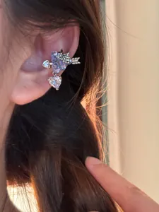 Dettaglio di un ear cuff con zirconi a forma di uva e cuore sull'orecchio di una modella