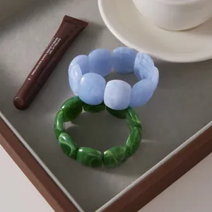 Set of two marbled resin stretch bracelets in blue and green, ideal for a layered look.
