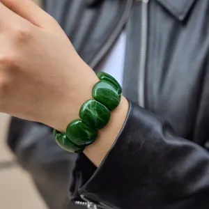 Close-up detail of a stylish chunky dark green resin bracelet worn on a female wrist
