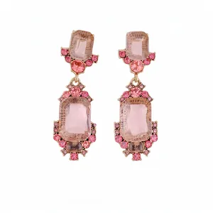 Orecchini pendenti geometrici rosa con strass e cristalli su sfondo bianco
