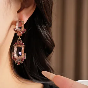 Primo piano di eleganti orecchini geometrici con strass rosa indossati sull'orecchio