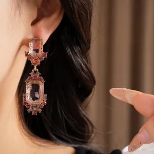 Dettaglio di eleganti orecchini pendenti in cristallo rosa su modella con montatura oro rosa