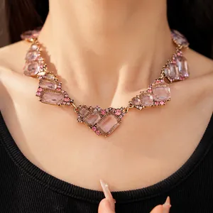 Primo piano di una collana di lusso con pietre geometriche rosa su una modella.