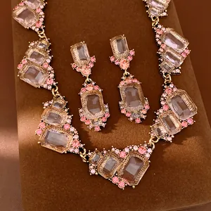 Dettaglio ravvicinato di un set di gioielli geometrici con cristalli rosa e oro