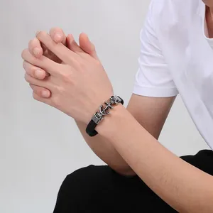 Men's braided black leather bracelet featuring a silver anchor and skull charm on a wrist
