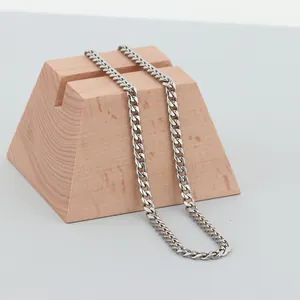 Minimalist stainless steel Cuban link chain necklace displayed on a wooden stand
