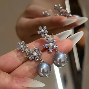 Gros plan détaillé des boucles d'oreilles fleur en zircon violet et perles grises