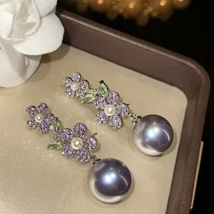 Détail de boucles d'oreilles florales vintage avec cristaux violets et grosses perles