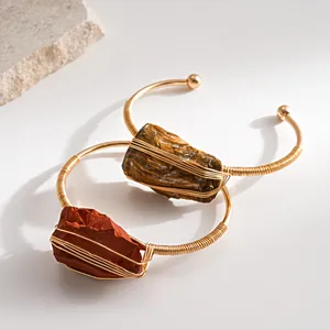 Detailweergave van vintage draadomwikkelde armbanden met tijgeroog en rode jaspis stenen.