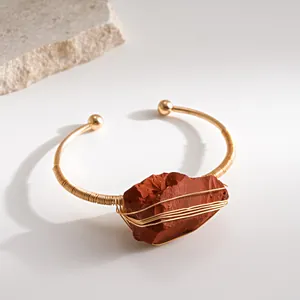 Gedetailleerde close-up van gouden wikkelarmband met natuurlijke rode jaspissteen