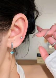 Close-up of silver zircon flower pendant earrings worn on ear for elegant style
