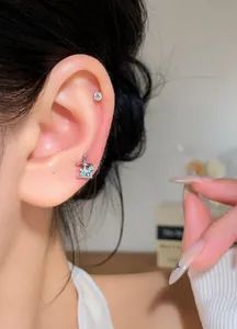 Close-up of a carousel ear stud with blue zircon and a round silver stud on ear