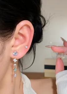 Detailed close-up of elegant star drop earrings with sparkling zircons worn on a model ear
