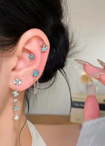Close-up detail view of blue zircon flower earrings set with silver needles on an ear.