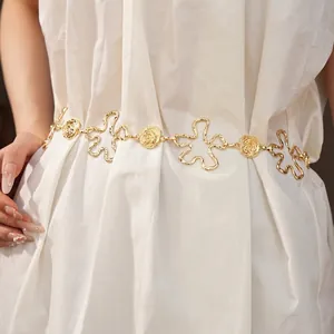 Chaîne de taille élégante en métal doré avec motifs fleurs ajourés sur vêtement blanc
