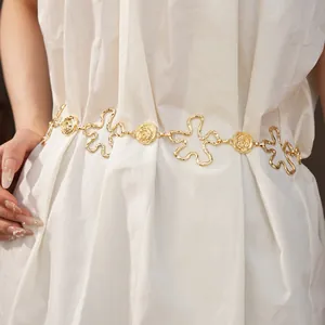 Détail d'une chaîne de taille en métal doré avec motifs fleurs évidées et roses