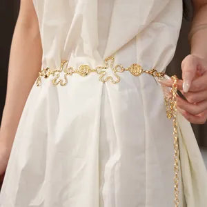 Détail d'une élégante chaîne de taille en métal doré avec fleurs sur robe blanche