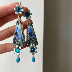 Close-up of vintage resin earrings featuring blue floral pattern and sparkling crystal accents
