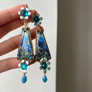 Close-up view of vintage floral earrings featuring blue crystals and iris pattern details.