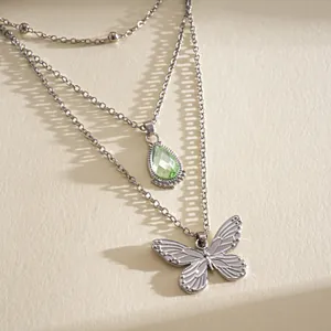 Détail d'un collier multicouche en acier inoxydable avec pierre verte et papillon chic