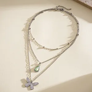 Vue détaillée d'un collier multicouche argenté avec pendentifs goutte verte et papillon