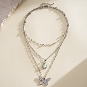 Vue détaillée du collier multicouche en acier inoxydable avec pendentifs goutte verte et papillon