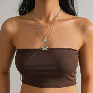 Détail d'un collier multicouche en acier inoxydable avec goutte verte et papillon