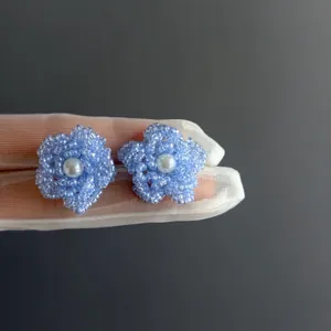 Détail rapproché de boucles d'oreilles fleur en perles bleues avec perle.