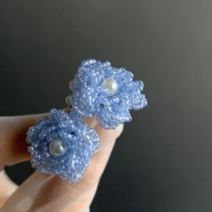 Gros plan détaillé de boucles d'oreilles fleur en perles de verre bleu avec perle.