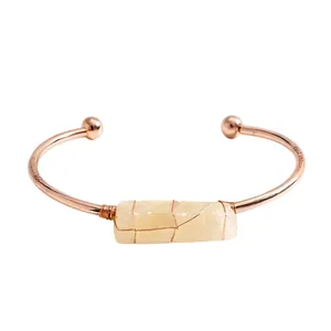 Elegante bracciale rigido in oro rosa con una pietra di cristallo giallo pallido avvolta in filo