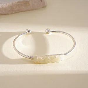 Dettaglio macro di cristallo giallo irregolare su bracciale rigido color argento