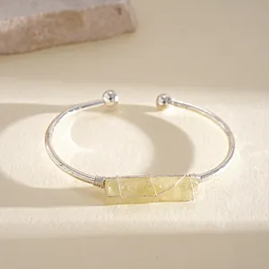 Primo piano di un bracciale rigido in argento con cristallo grezzo giallo avvolto