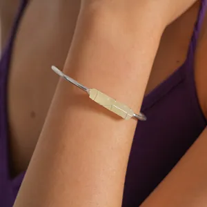 Macro dettagliata di un cristallo grezzo irregolare avvolto su un bracciale rigido d'argento