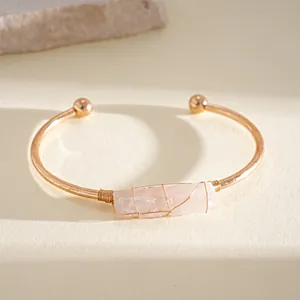 Dettaglio di un bracciale rigido dorato con cristallo rosa e finitura elegante