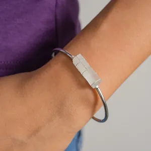 Primo piano di un bracciale rigido in argento con un dettaglio di cristallo bianco