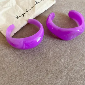 Detailopname van twee paarse onregelmatige acryl armbanden op een getextureerde stof.