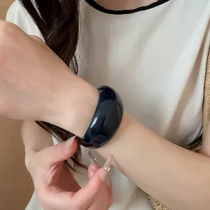 Close-up van een dikke donkerblauwe acryl onregelmatige armband om een vrouwenpols
