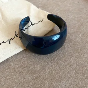 Detailopname van een glanzende marineblauwe acryl manchetarmband op een linnen tas