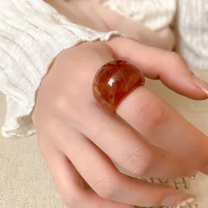 Detailed close-up view of a chunky amber resin ring with unique marbled texture worn on a hand