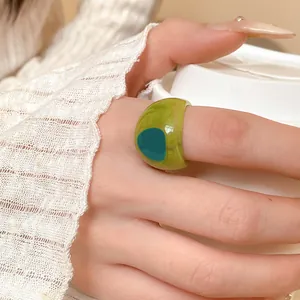 Detailed close-up of a translucent green resin ring with artistic marble swirl pattern on hand