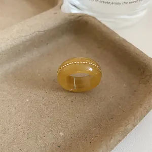 Close-up detail of an amber translucent resin ring featuring gold beaded metal inlay