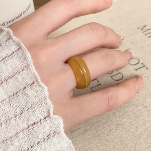 Close-up of amber resin ring with golden bead detail on an Asian hand